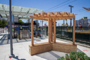 A temporary wooden shade structure set up at an LA metro station