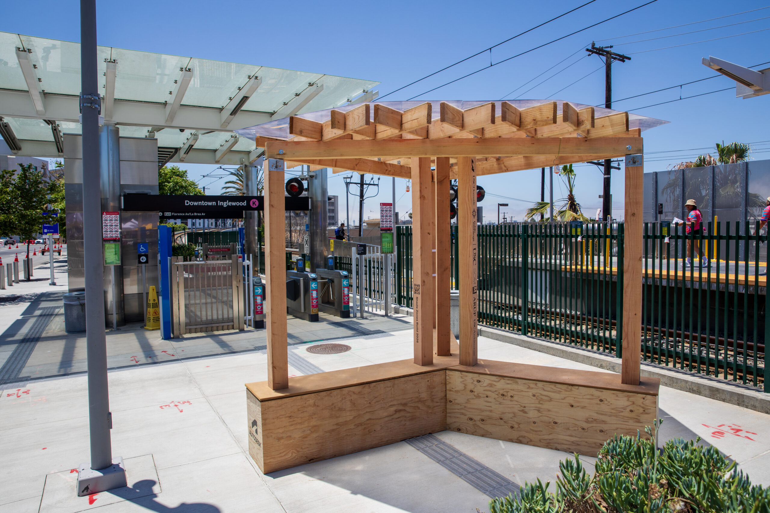 A temporary wooden shade structure set up at an LA metro station