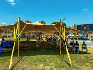A temporary shade structure with people sitting under it in an LA park