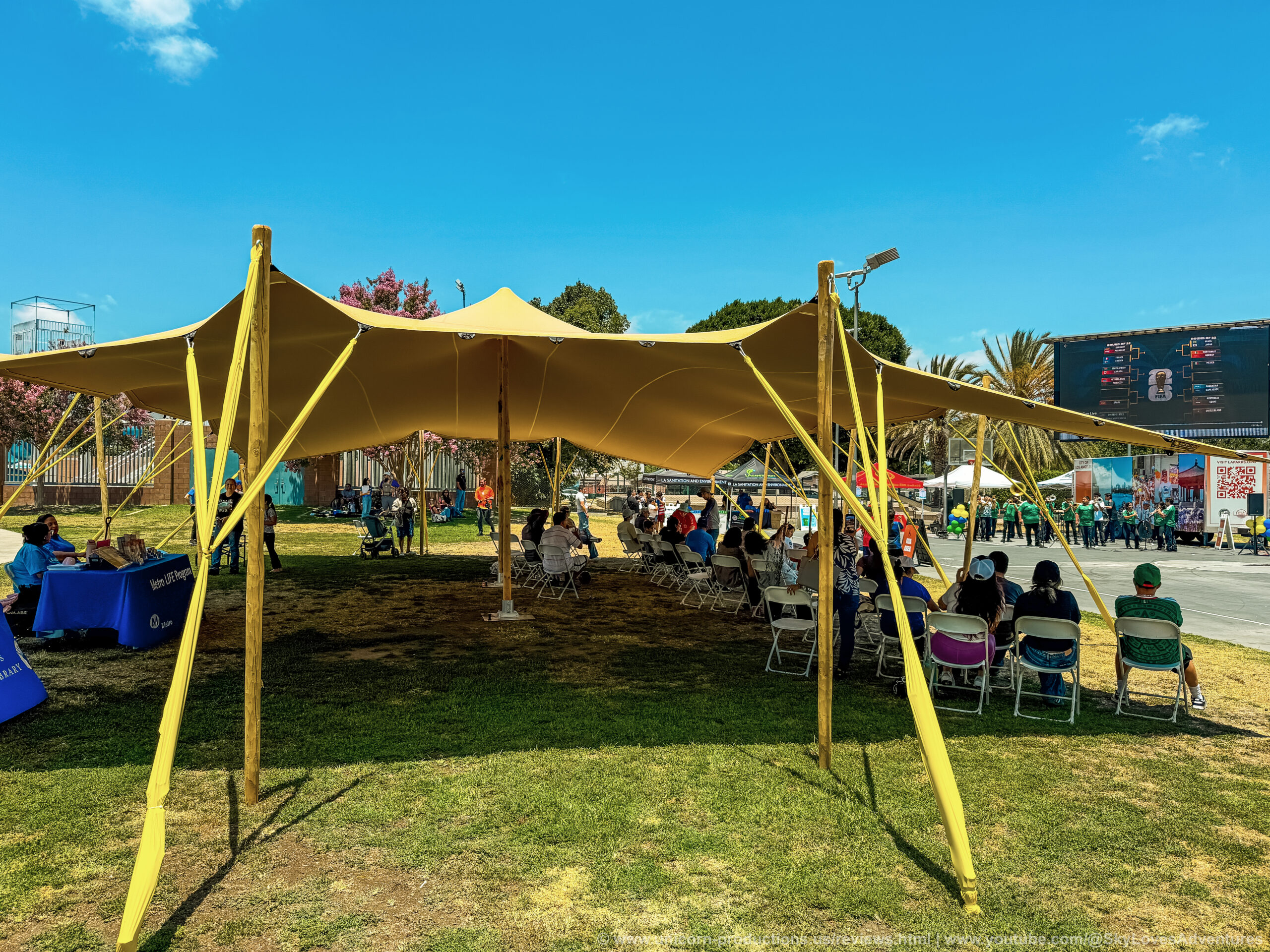 A temporary shade structure with people sitting under it in an LA park